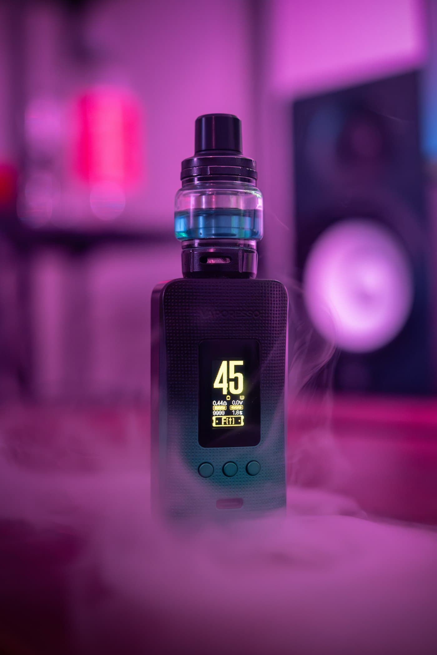 Close-up of a vape mod and tank with its display lit up and vapour drifting past