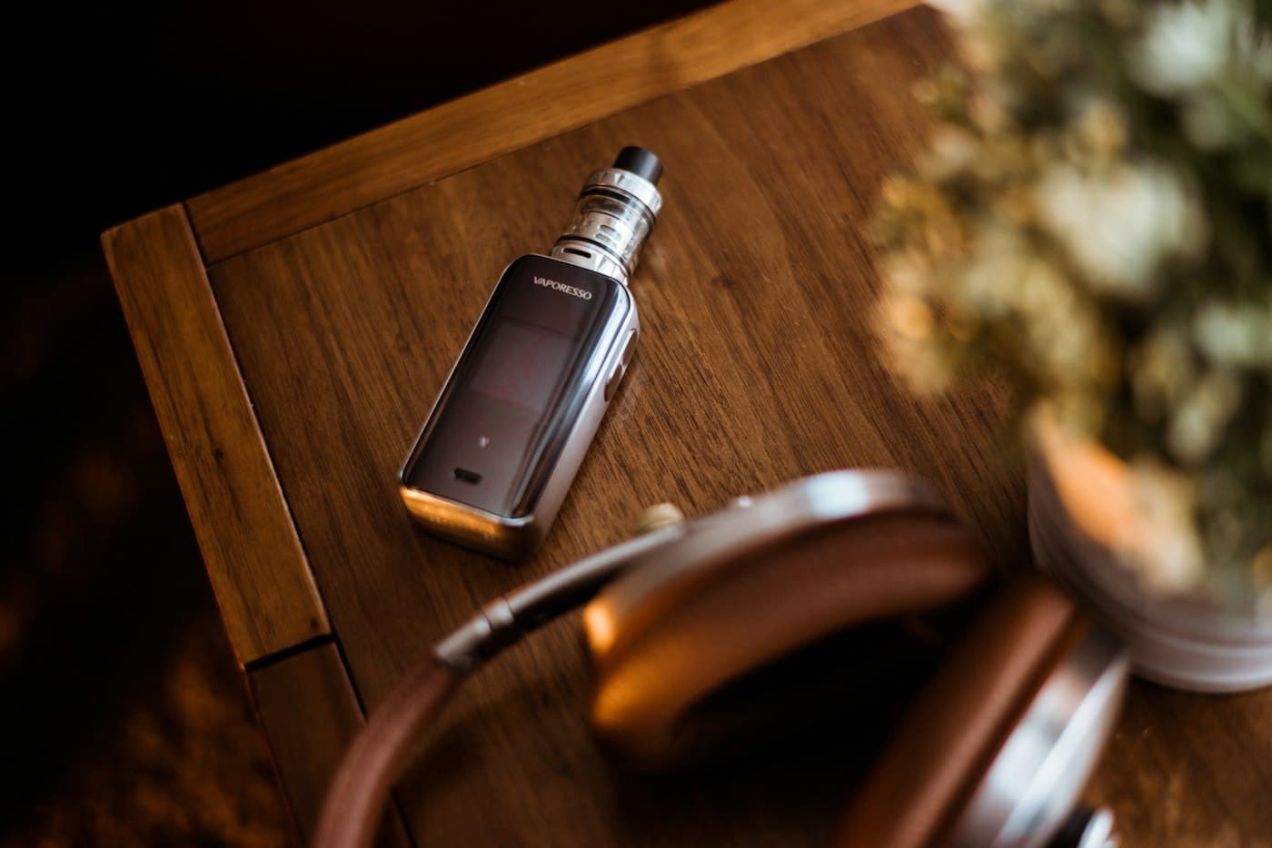 Compact vape mod device with an e-liquid bottle on a wooden table