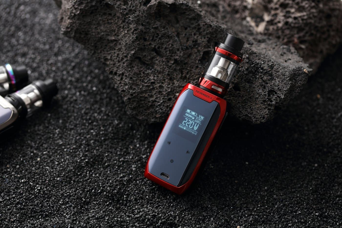 Close-up of a black pod mod device resting on a dark wooden surface